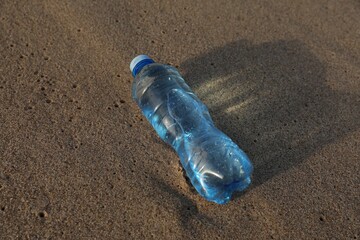 Plastic bottle of fresh water on wet sand
