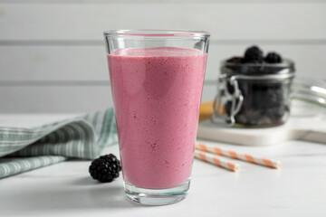 Glass of blackberry smoothie on white table