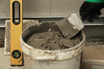 Worker taking adhesive mix with spatula, closeup