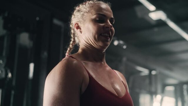 A Focused Female Bodybuilder Lifts Barbell with Heavy Weights in a Hardcore Gym Workout. Portrait of Powerlifter Improving Her Endurance and Strength by Training and Exercising. Slow Motion Shot