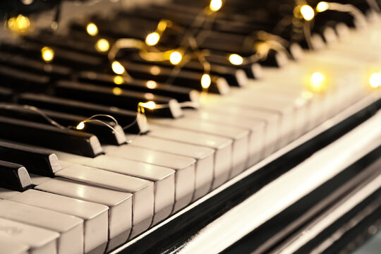 Piano keys with glowing Christmas lights, closeup