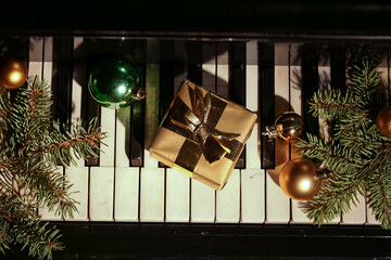 Gift with Christmas balls and fir branches on piano keys, top view