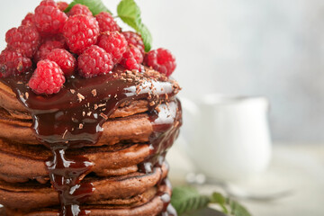 Chocolate Pancakes. Pancakes with fresh raspberry with chocolate glaze or toppings in gray bowl on light gray table background. Homemade classic american pancakes. Page for magazine concept.