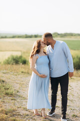 Fototapeta premium Portrait of a lovely couple standing together on the greenfield. Happy couple expecting a baby, young family concept