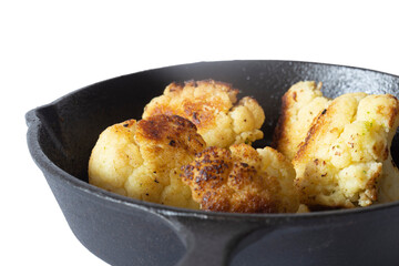 Cauliflower fried, in a cast iron frying pan with olive oil. Isolated on a white background