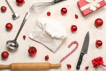 Chef's hat with utensils, Christmas balls and gift on light background