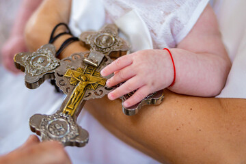 Christian baby hands over a priest's golden silver cross in a church. Child baptism christening....
