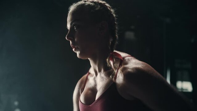 An Energetic Female Athlete Running in Place as a Cardio Exercise for Daily Workout in a Dark Gym. An Agile Future Roadrunner Training Hard For the Next Competition. Dynamic Tracking Shot