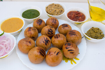 Litti in white plate with tomato, brinjal, potato, pointed gaurd and coriander chutney or chokha...