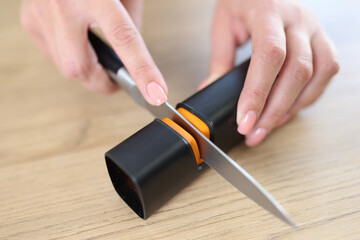 Female hands sharpening knife with special knife sharpener