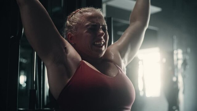A Persistent Female Bodybuilder Enduring the Workout Pain of Exercising. Portrait of a Woman Challenging Gender Stereotypes And Lifting Heavy Weights and Training with Lat Pull Down Machine