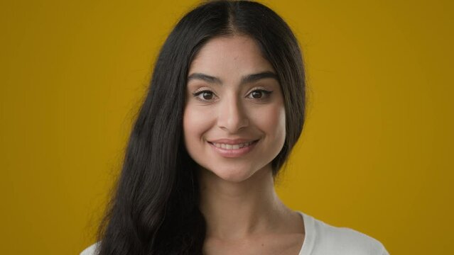 Closeup portrait headshot in yellow studio background 20s Indian ethnic woman girlfriend lady female girl model client customer smile friendly facial expression smiling cosmetology dermatology make-up