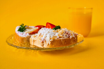 2 sandwich with different spread and glass of juice on yellow background.