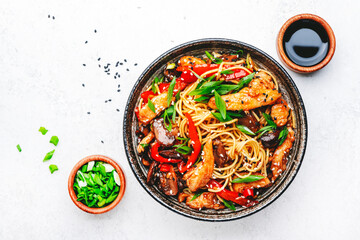 Stir fry egg noodles with chicken, sweet paprika, mushrooms, chives and sesame seeds in bowl. Asian cuisine dish. White table background, top view