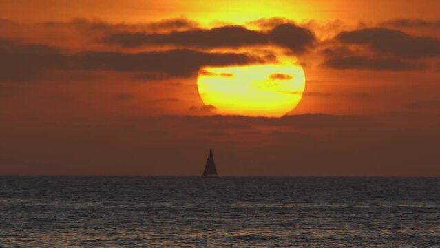 Beautiful evening sunset with a big sun and a sailing yacht in the Atlantic Ocean on the coast of Portugal. 