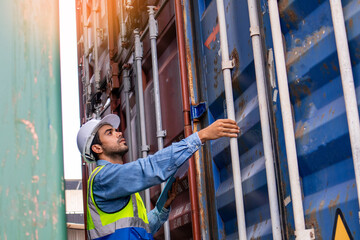 Fototapeta na wymiar A worker in safety helmets and uniform working in a container port terminal. A handsome male engineer checking products in cargo containers before exporting to the harbor.
