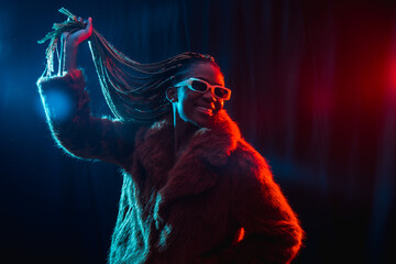 Black ethnic woman with braids with blue and red led lights, model having fun and dancing