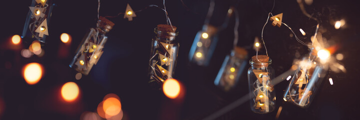 Christmas garland with golden lights in darkness. String of lights in glass cylinders with sparkler...