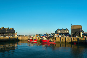 Whitstable, Kent, UK - October 6 2022 - Two red boats in Whitstable Harbour - obrazy, fototapety, plakaty