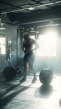 Professional Female Powerlifter Successfully Lifting a Heavy Barbell While Exercising and Training. Athletic Strong Woman Walking towards Weights and doing her Workout. Static, Vertical shot