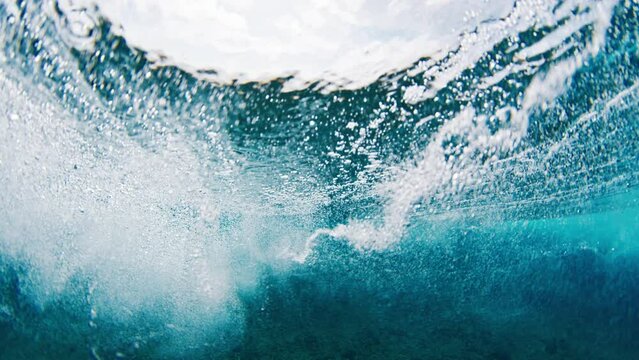 Above and underwater view of the breaking ocean wave in the Maldives. Clear wave breaks on the shore