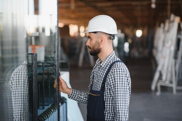 Portrait of workerin coverall working with PVC window at factory