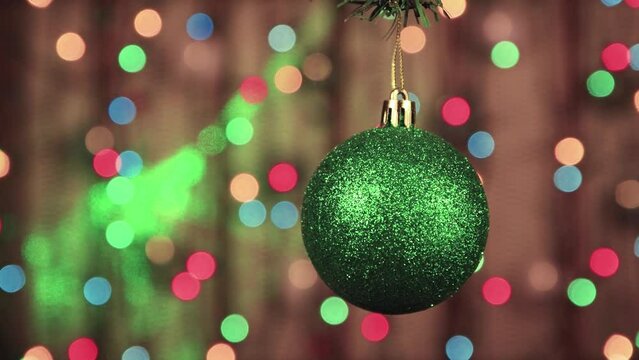 Close-up of green Christmas balls on a background of twinkling lights. New Year's multi-colored garlands in defocus. Holiday card with bokeh. Abstract background for captions and text. UHD 4K.