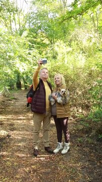 Vertical video of a mature couple carrying a Yorkshire dog and taking a selfie in the forest