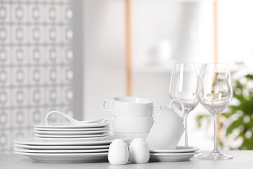 Set of clean dishware and glasses on light grey table, space for text