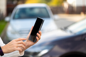 woman with smartphone standing next to the car, using mobile app for paying, car lock  or Internet