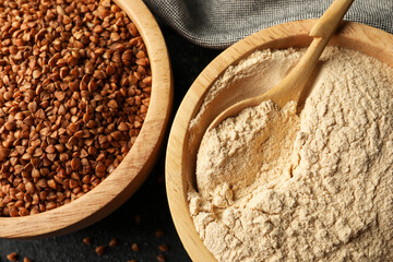 Buckwheat flour and grains in bowls on black table, top view
