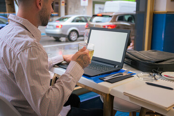 Close- up of a man working remotely with a laptop from a restaurant