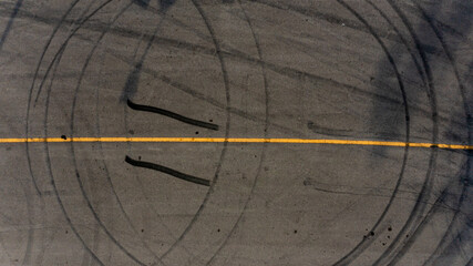 Top view tire tracks texture and background. Asphalt texture with line and tire marks. Automobile automotive tire skid mark on race track. Abstract texture car drift tire skid mark. © Darunrat