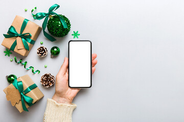 christmas mockup with space for text. christmas advertising, app template. hand holding phone with empty screen on table background. Happy New Year and Xmas Flat lay - obrazy, fototapety, plakaty