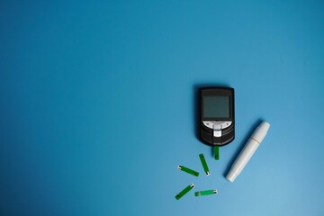 glucometer for checking blood sugar. Diabetes concept on blue background