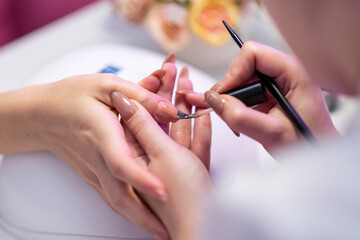 Obraz na płótnie Canvas Close-up of a girl doing a manicure in a beauty salon. Nail care. Manicurist applies varnish on the nail. Hardware manicure revealed. Cosmetic procedure