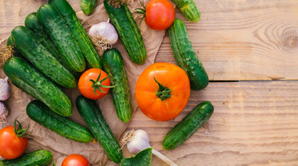Fresh vegetables on a wooden background. The concept of healthy eating. Cucumbers, tomatoes, garlic, dill. Top view.
