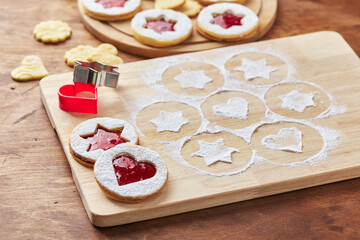 Wooden cutting board with powdered sugar and Linzer cookies, baking decoration process
