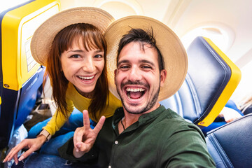 Happy tourist taking selfie inside airplane - Cheerful couple on summer vacation - Passengers...