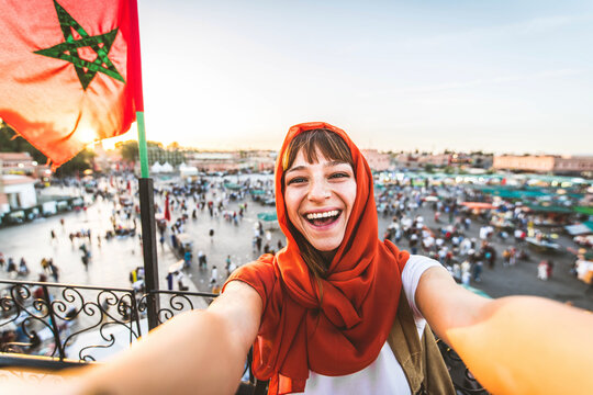 Happy tourist visiting Jamaa el-Fna market, Morocco - Beautiful female taking selfie enjoying summer vacation outside - Holidays and travel blogger concept