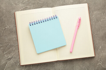 Open notebook and notebooks on grey background.