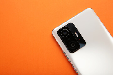 Fototapeta premium White smartphone on orange background. Top view