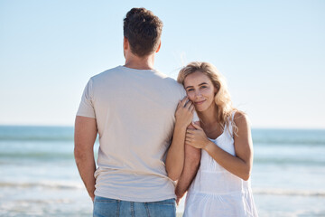Love, beach and couple on vacation hug by ocean on luxury summer holiday trip to relax. Back of man, woman with happy smile on date for romance, peace and celebrate bond on blue sea water background