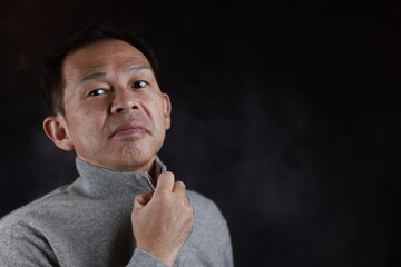 Middle-aged Japanese man in gray turtleneck wool sweater. Concept image of Warm Biz, stability in daily life, and sustainable living.