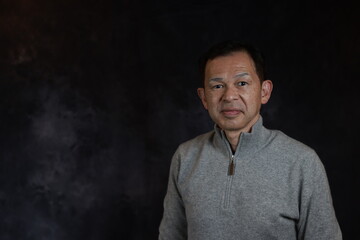 Obraz premium Middle-aged Japanese man in gray turtleneck wool sweater. Concept image of Warm Biz, stability in daily life, and sustainable living.
