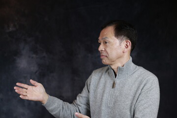 Middle-aged Japanese man in gray turtleneck wool sweater. Concept image of Warm Biz, stability in daily life, and sustainable living.
