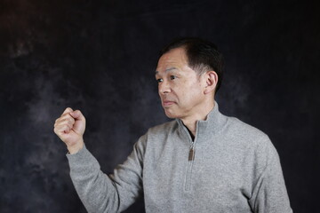 Middle-aged Japanese man in gray turtleneck wool sweater. Concept image of Warm Biz, stability in daily life, and sustainable living.