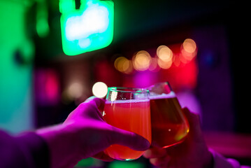 Two friends hands with glasses of craft beer at the pub or bar. taproom