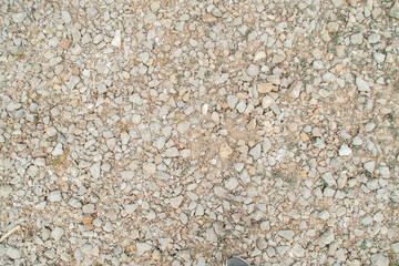 Background with gravel and grass growing between the stones. Small pieces of granite scattered on the ground.