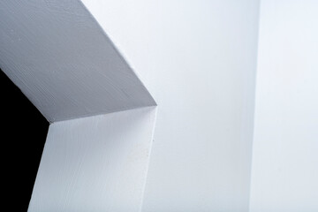 Close-up of the corner of a doorway in the wall. The wall is covered with white plaster. Geometric light background on the theme of architecture and construction.